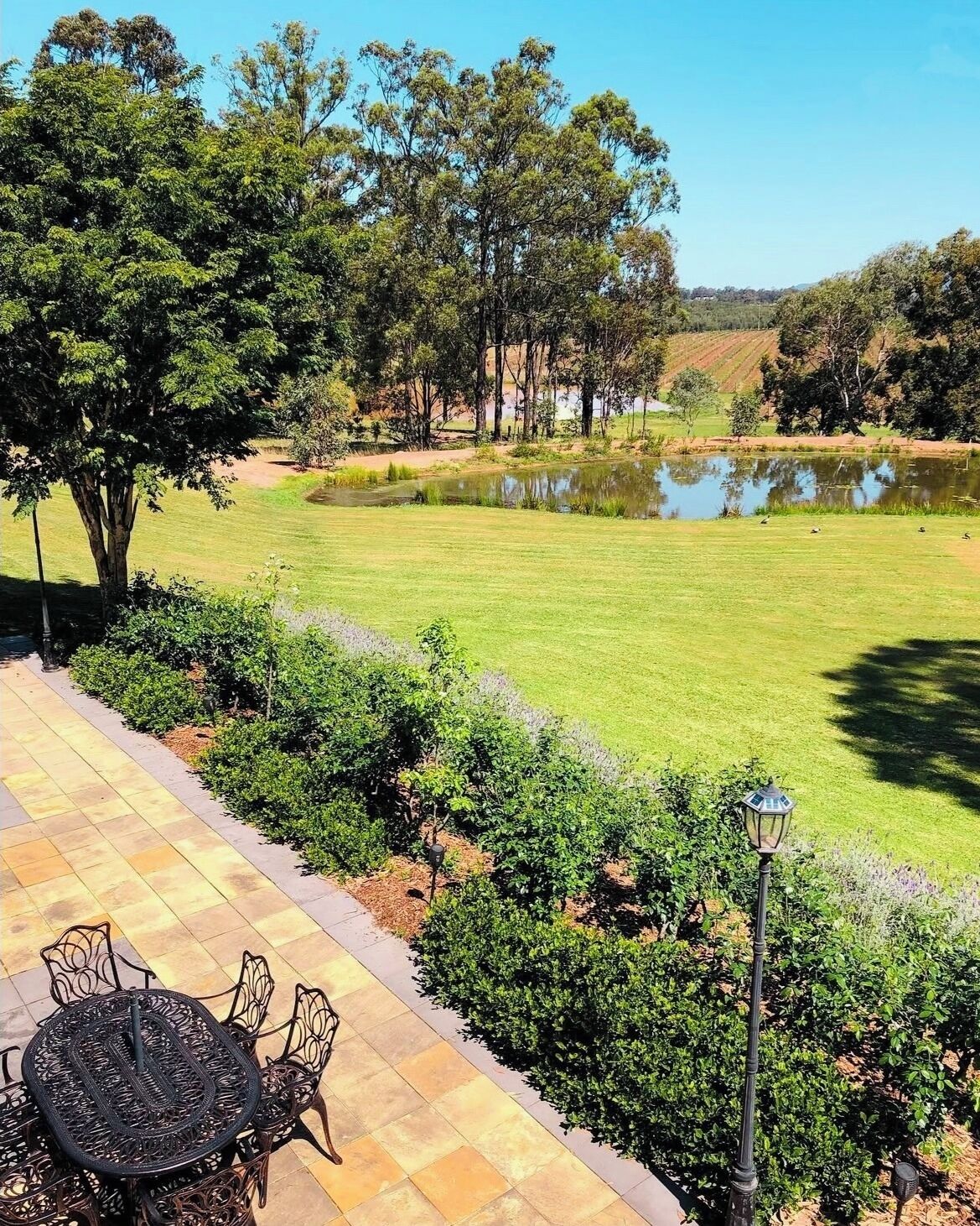 A patio area with a table and chairs, surrounded by a well-maintained lawn and trees.