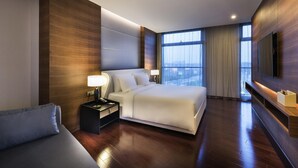 Een moderne hotelkamer met een groot bed, nachtkastjes, een flatscreen televisie en een groot raam met uitzicht op de stad.