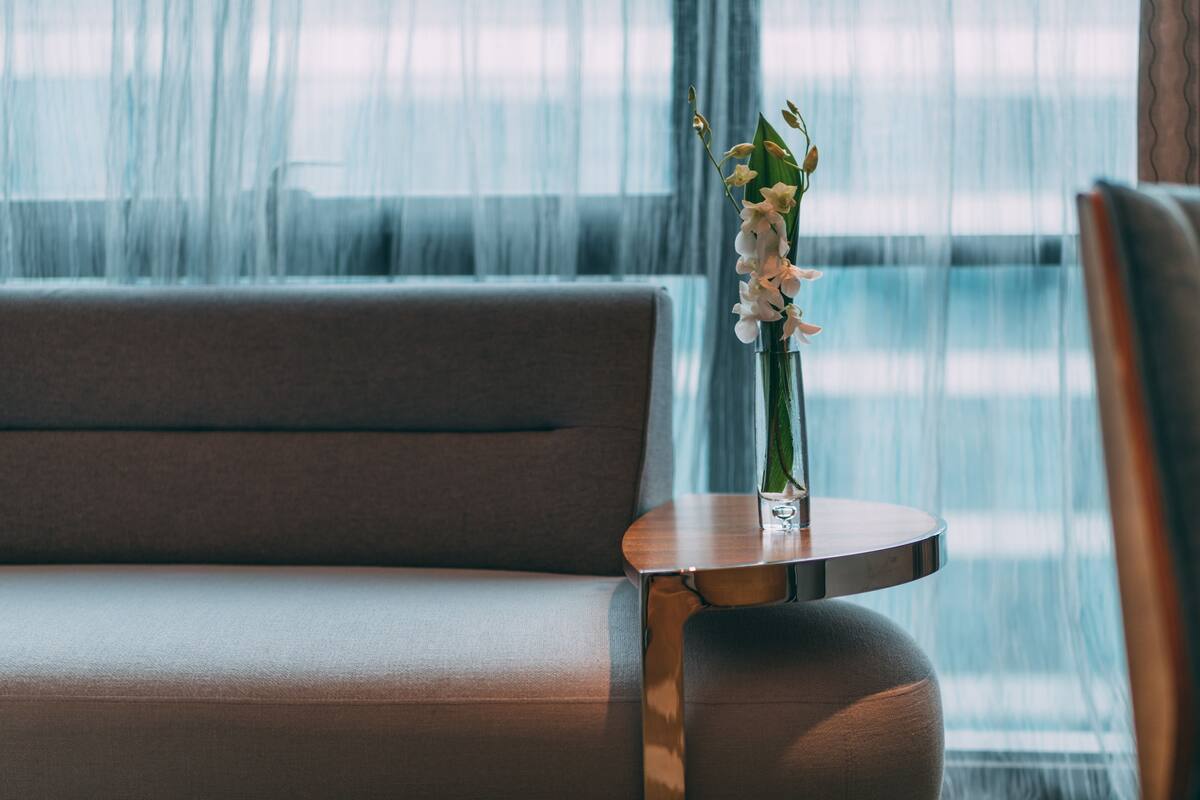 Ein modernes Zimmer mit einer Couch und einem kleinen Tisch mit einer Blumenvase.