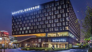 Een modern hotel met een opvallend 'NOVOTEL' bord, meerdere verdiepingen en een goed verlichte ingang.