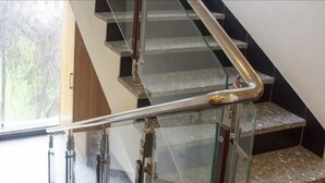 A staircase with glass railings and metal handrails. - Meadows (Varanasi)