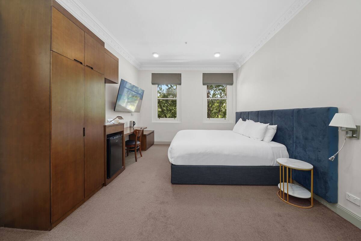 Une chambre à coucher comprenant un lit, un bureau, une chaise, une armoire et un téléviseur.