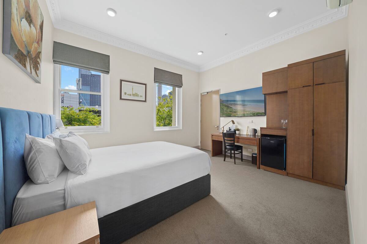 Une chambre d’hôtel avec un lit, un bureau et une armoire.