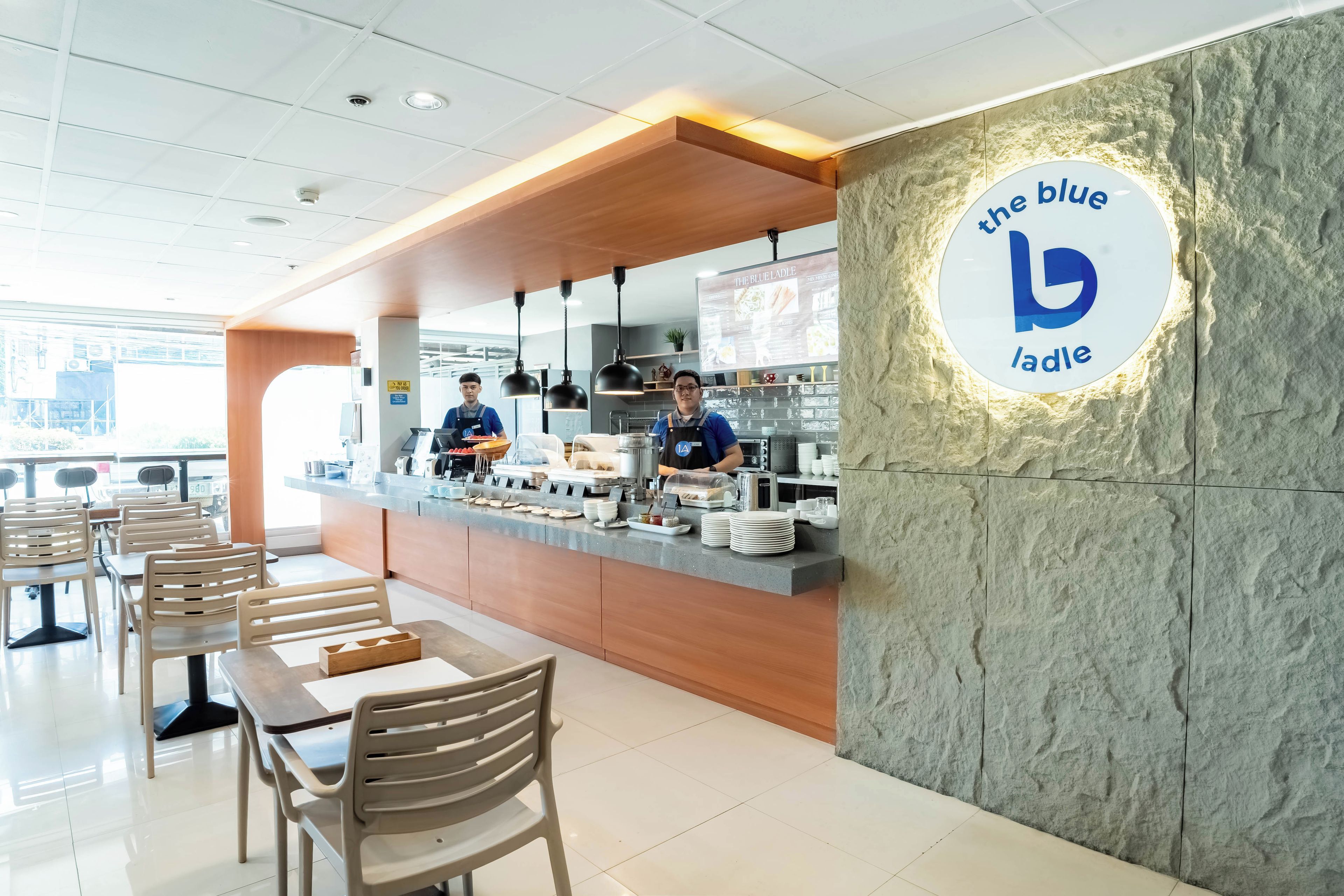 A cafe interior with a counter, seating area, and a wall with a logo.