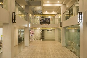 A spacious, multi-level atrium with glass railings, a patterned floor, and a banner advertising a grand opening. - 1A Express Hotel (Cagayan de Oro)