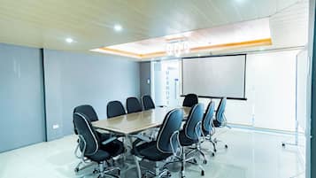 A conference room with a long table, six chairs, a whiteboard, and a glass partition.