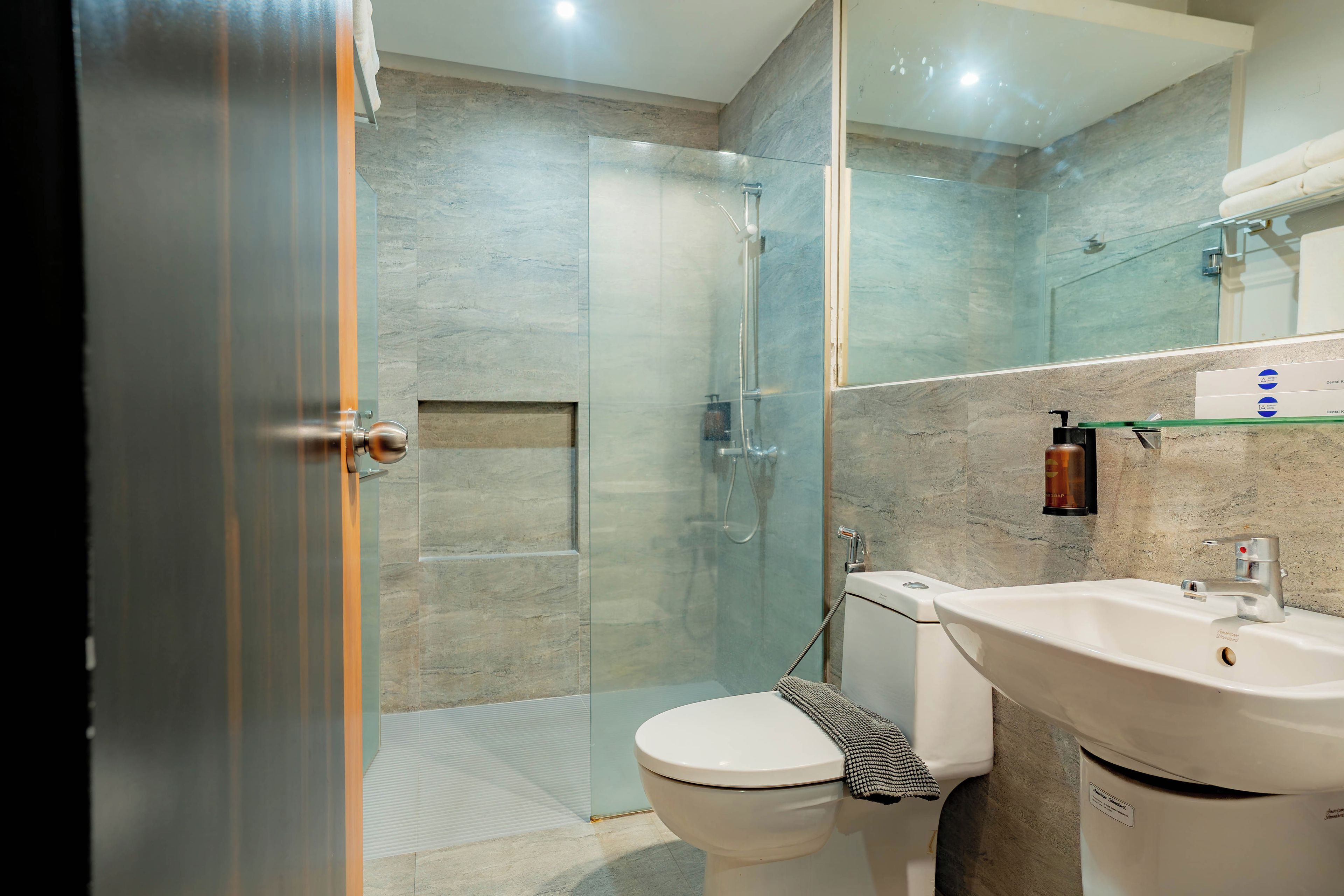 A modern bathroom with a glass shower enclosure, a white toilet, and a sink with a soap dispenser.