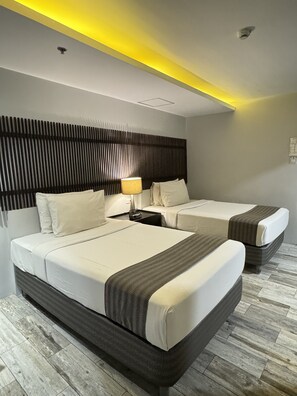 A hotel room with two beds, a modern headboard, a nightstand, and a lamp. - 1A Express Hotel (Cagayan de Oro)
