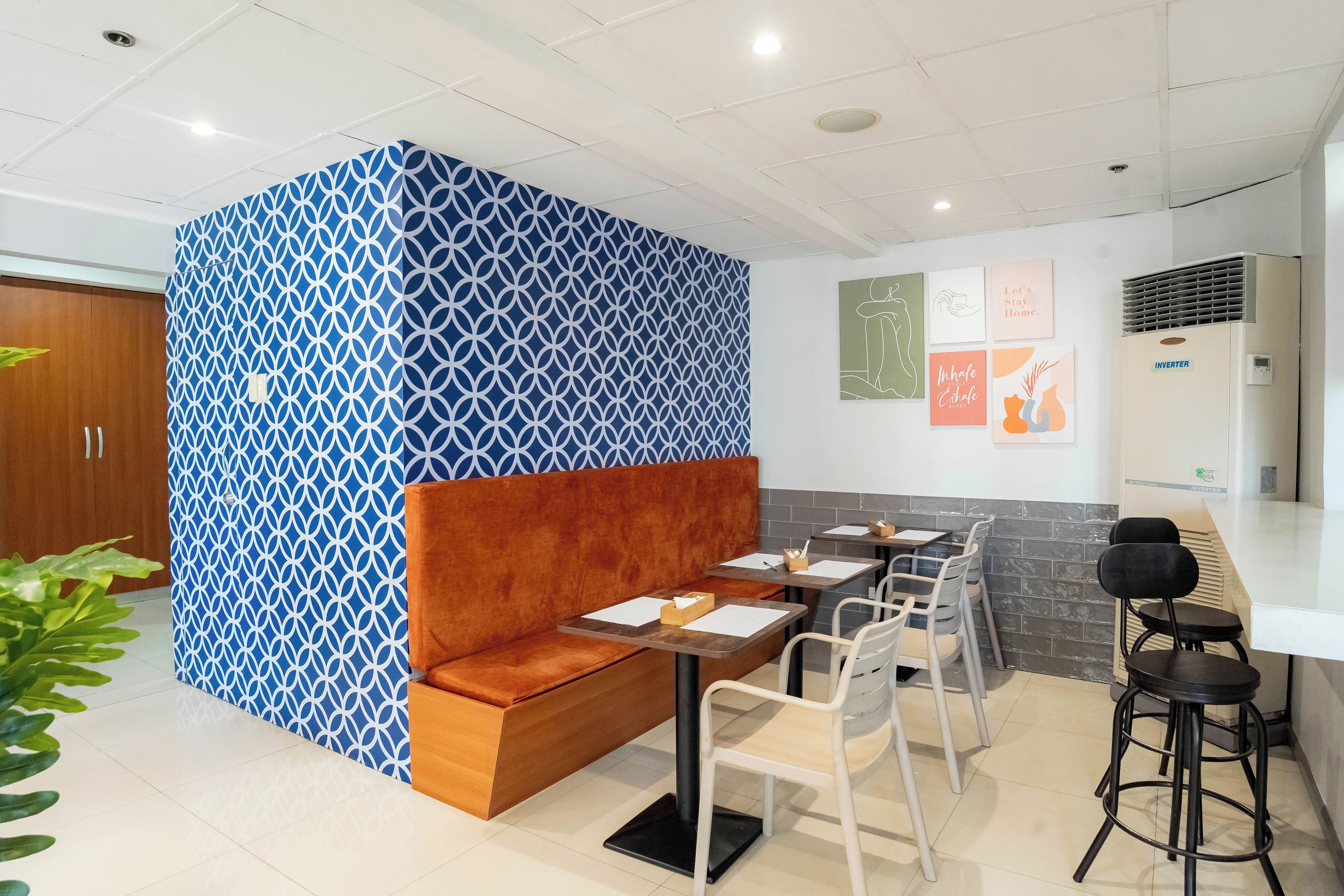 A modern interior with a patterned partition, seating area, tables, chairs, and artwork on the walls.