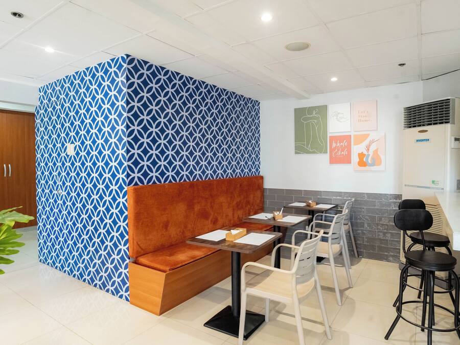 A modern interior with a patterned partition, seating area, tables, chairs, and artwork on the walls.
