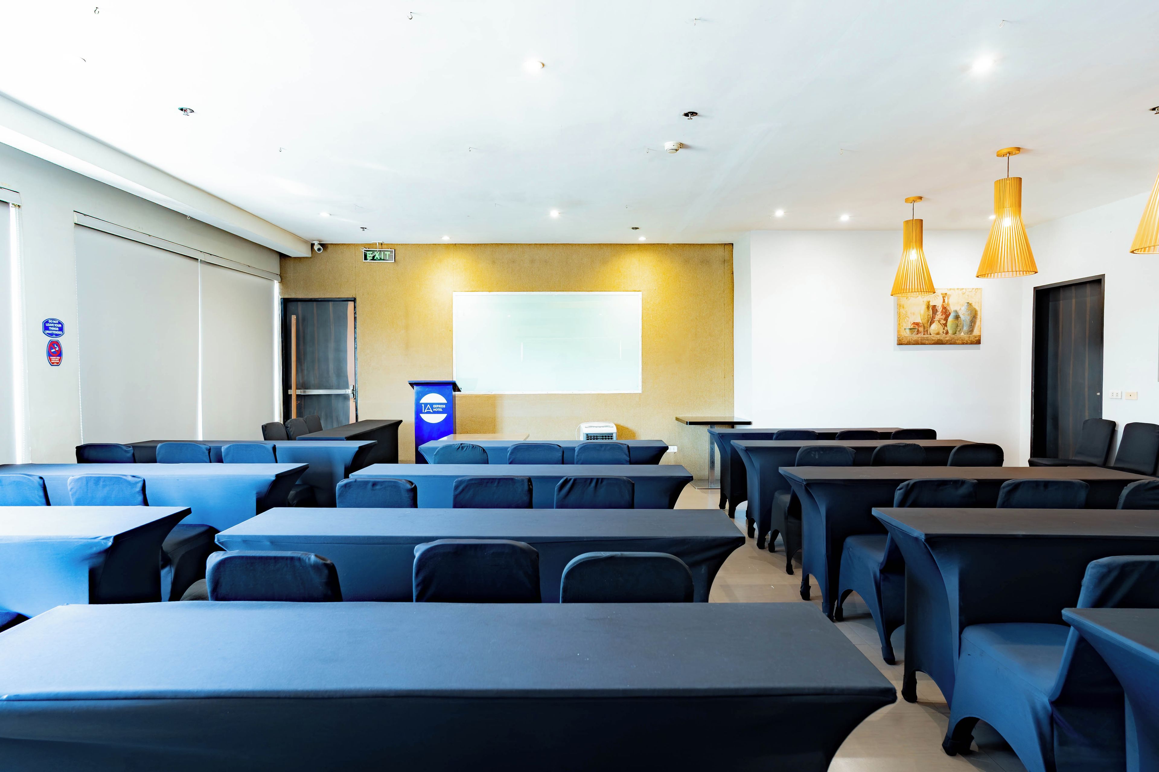 Ein Konferenzraum mit Tischen und Stühlen, einem Rednerpult und einer Projektionsleinwand.