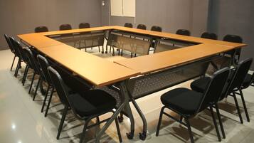 A conference room with a long table, black chairs, and a projector screen.