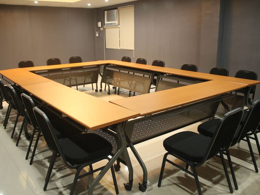 A conference room with a long table, black chairs, and a projector screen.
