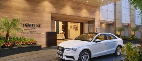 A white Audi car parked in front of a building with a sign reading "Fortune Park" and "Haridwar Member ITC's hotel group".