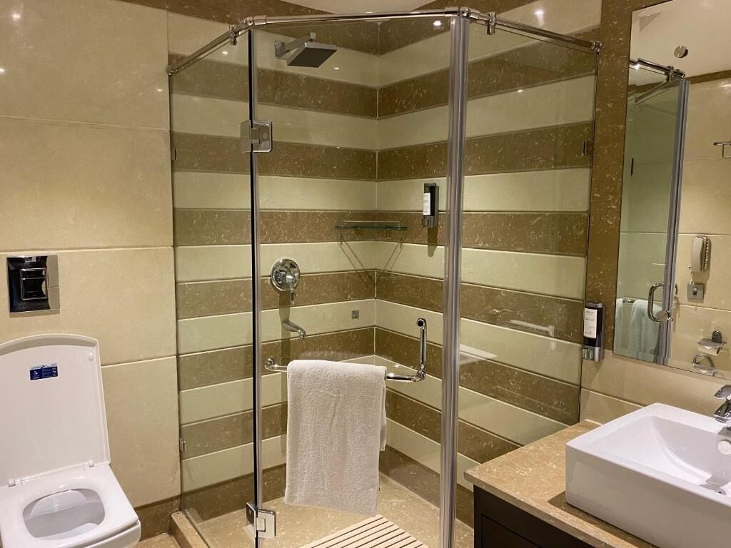 Een moderne badkamer met een douchecabine van glas, een wit toilet en een wastafel met spiegel.
