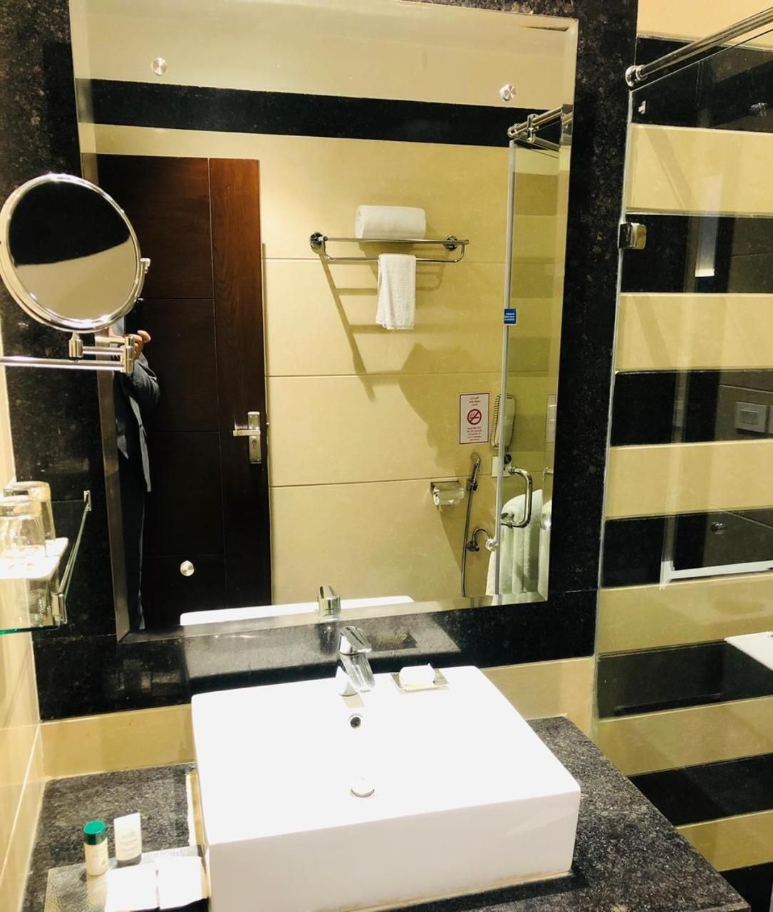 A bathroom with a white sink, a mirror, a towel rack, and a shower area.
