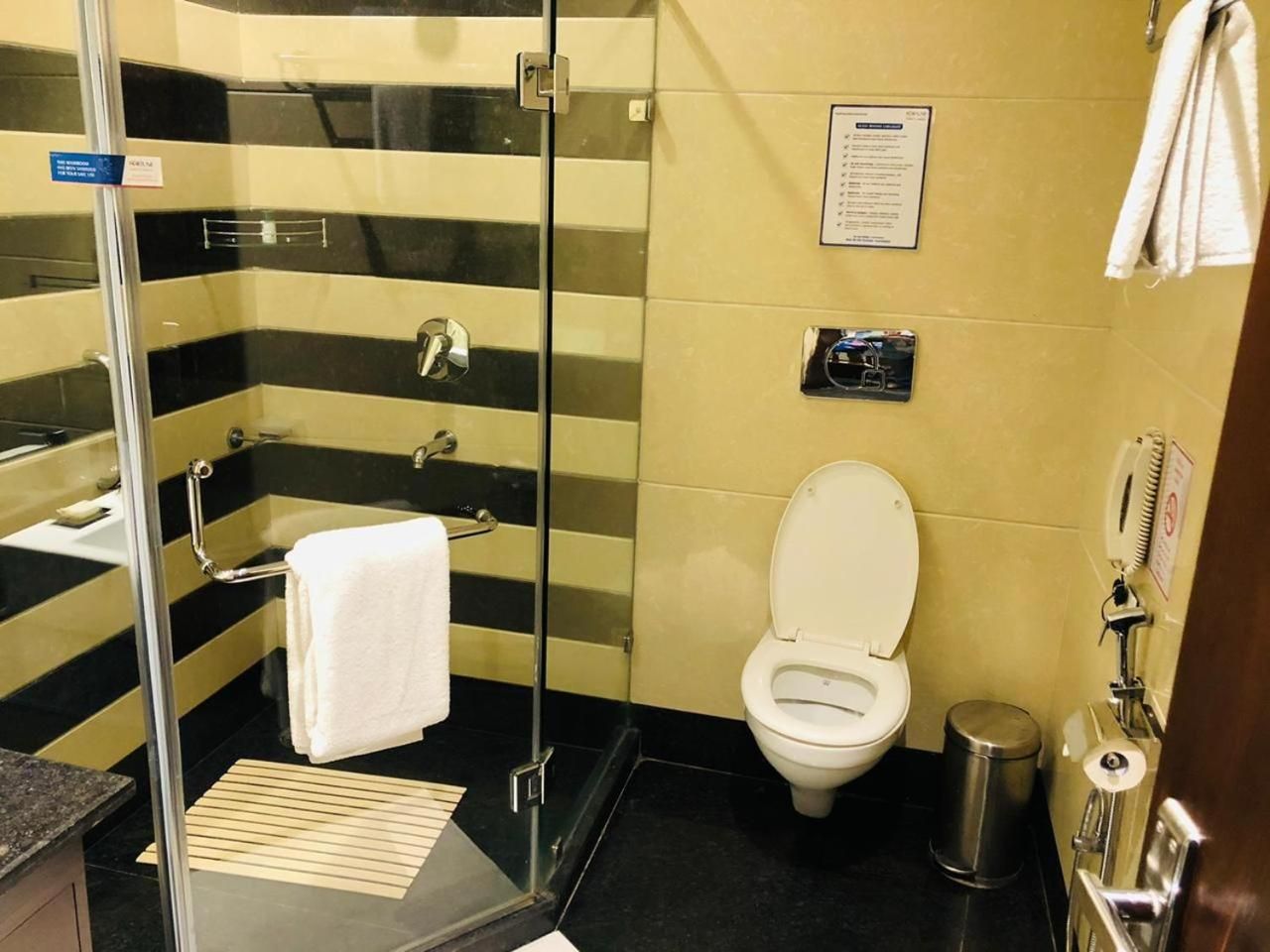 Ein Badezimmer mit Duschkabine aus Glas, einer weißen Toilette und einem Mülleimer.