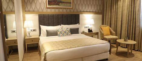 A hotel room with a large bed, two bedside tables with lamps, a chair, and a painting on the wall.