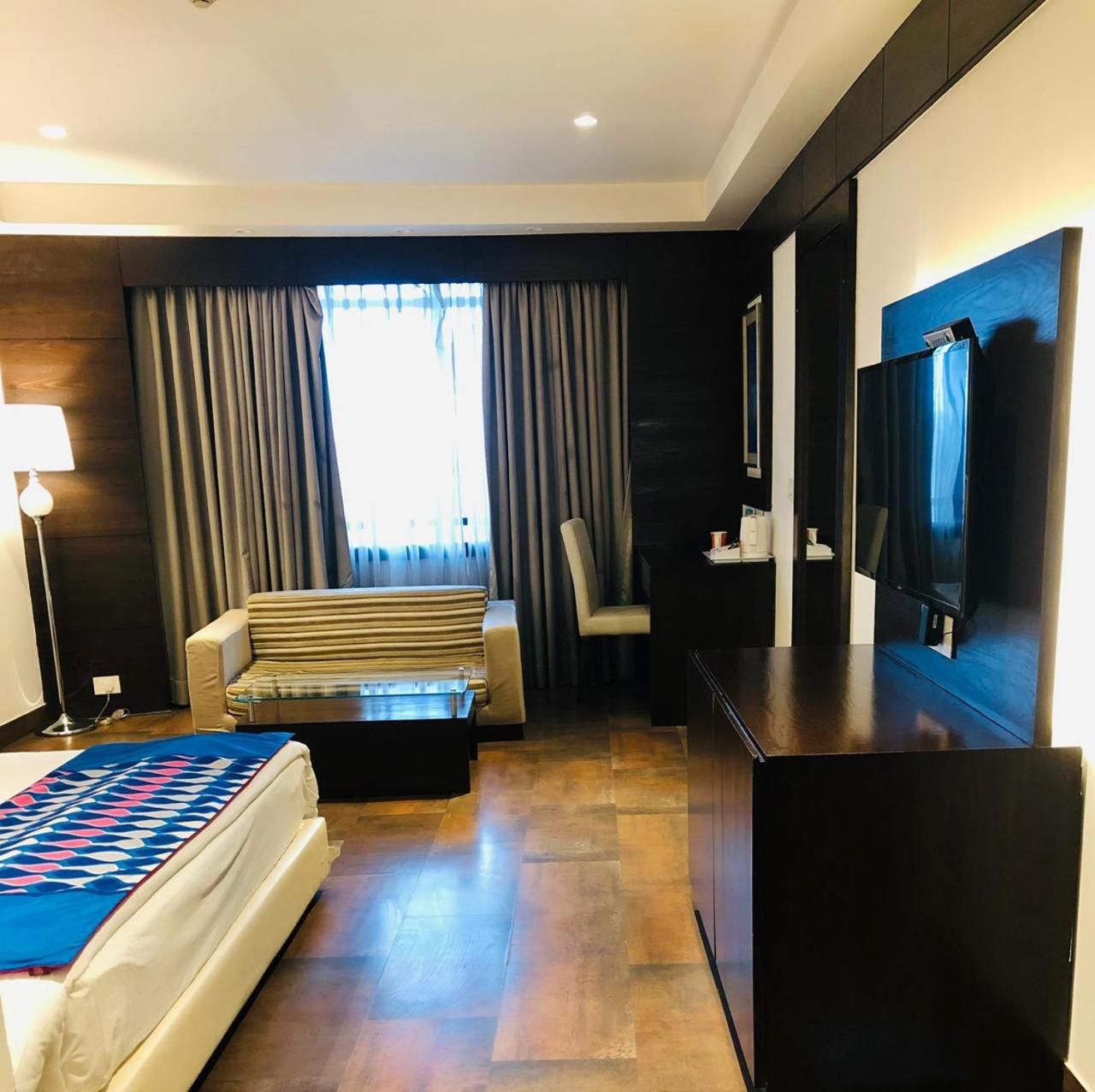 Une chambre d’hôtel comprenant un lit, un canapé, une table basse, une télévision et un bureau.