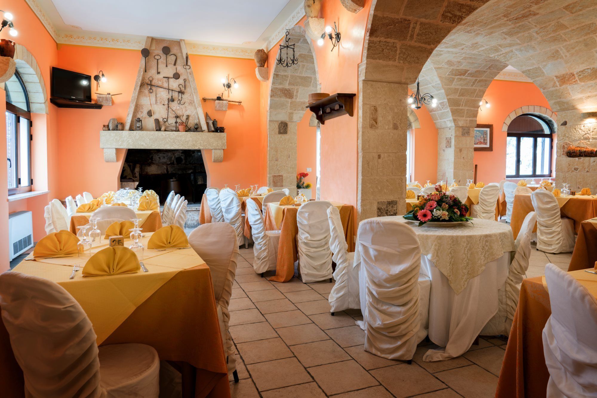 A banquet hall with round tables, white and yellow tablecloths, and chairs with white and yellow covers.