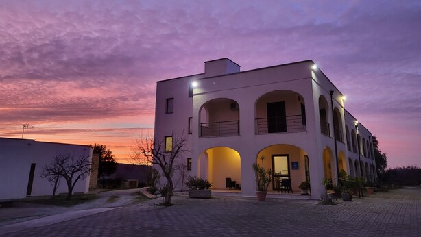 A modern building with a courtyard, featuring a central open space with seating and potted plants. - Hotel Salento (Specchia)