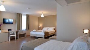 Una habitación de hotel con cama, escritorio, silla, televisor y lámpara de noche.