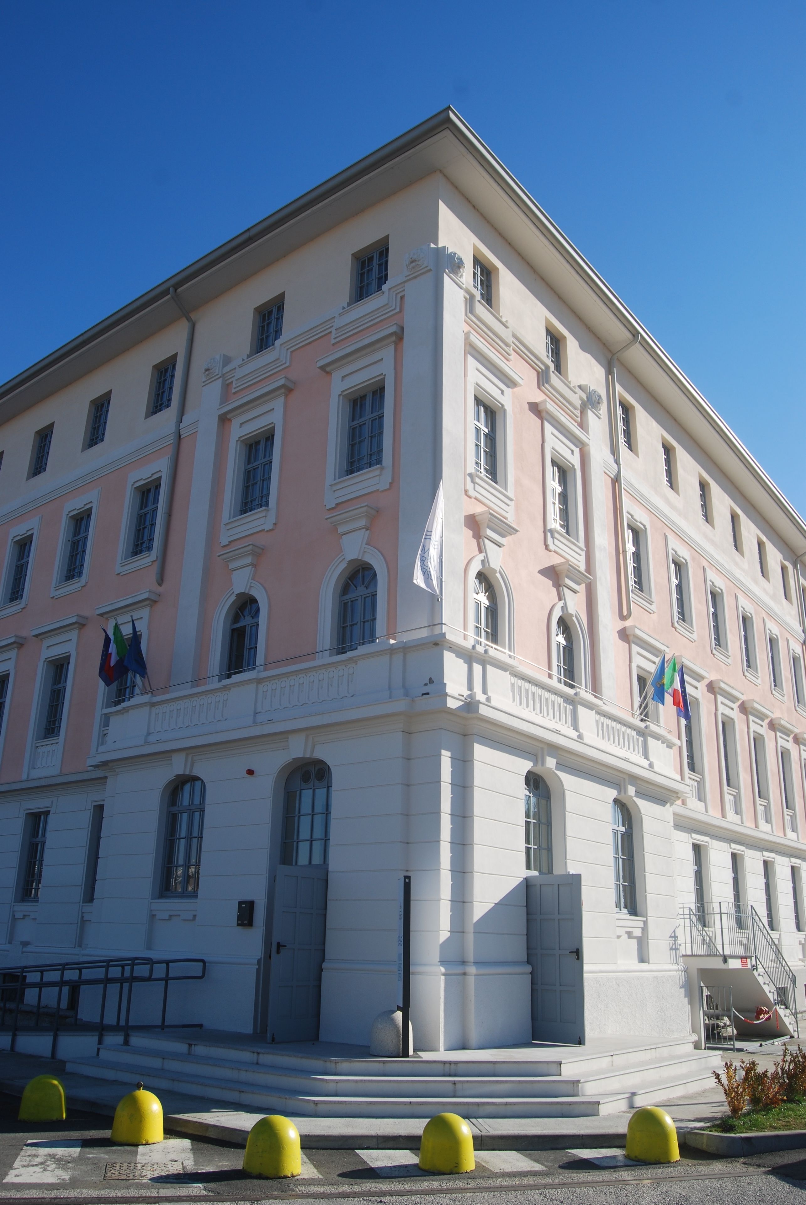 Un edificio de varios pisos con fachada rosa, detalles blancos y múltiples ventanas.