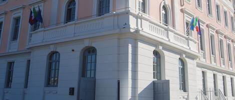 Un edificio de varios pisos con fachada rosa, detalles blancos y múltiples ventanas.