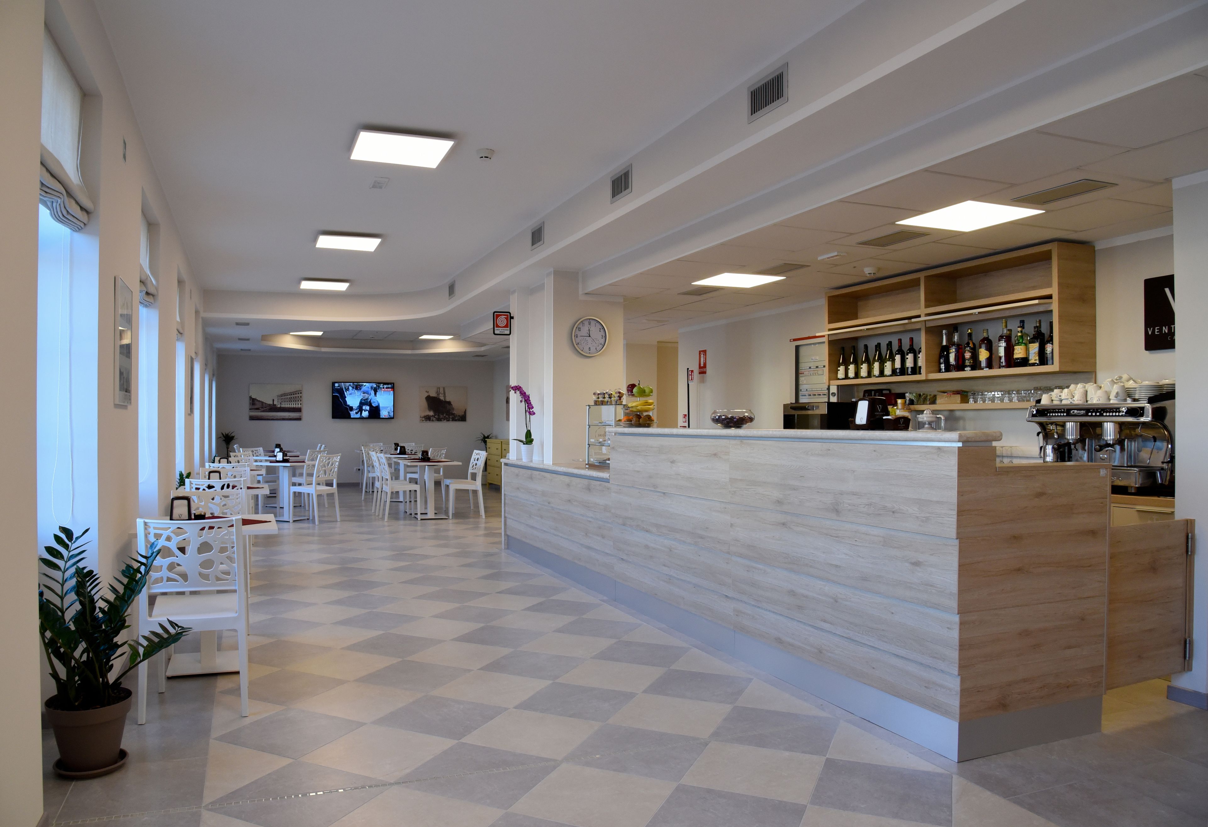 Un hall espacioso con suelo a cuadros, una recepción y una zona de bar con estanterías llenas de botellas.