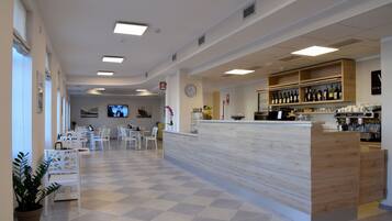 A spacious lobby with a checkered floor, a reception desk, and a bar area with shelves of bottles.