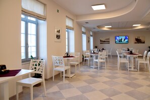 Enjoy meals and meetings in this stylish room with a checkered floor, white furniture, and a flat-screen TV.