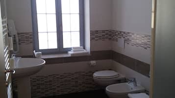 Un baño con ventana, lavabo, inodoro y bidé.