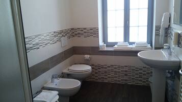 Un bagno con toilette, bidet e lavandino. Si vede una finestra con vista sull'esterno.