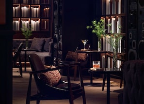 A cozy lounge area with leather chairs, a sofa, and a bookshelf filled with books.
