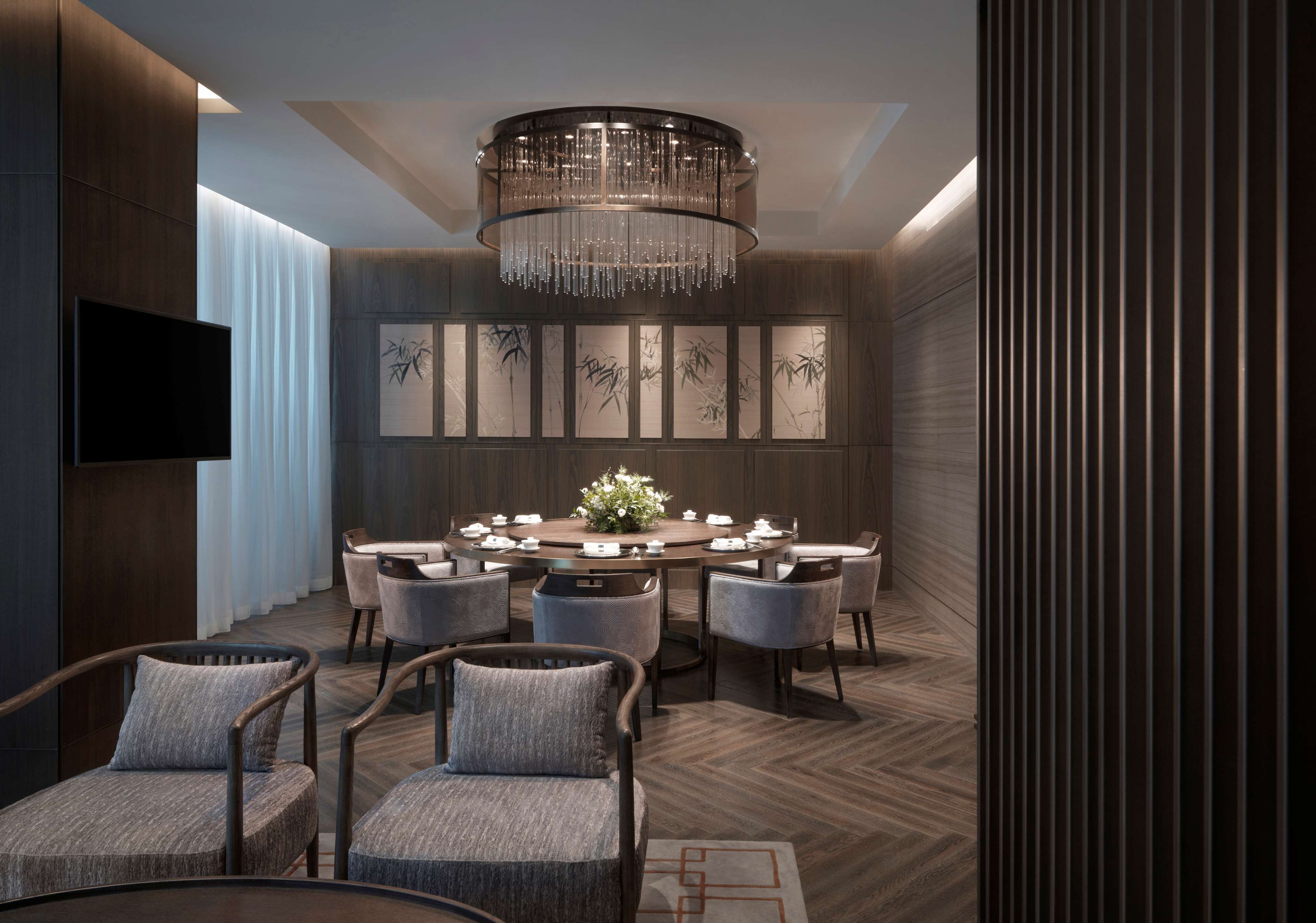 A modern dining area with a round table, chairs, and a chandelier.