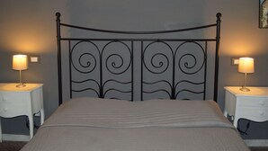 Un lit avec une tête de lit en métal, deux tables de chevet et une lampe de chaque côté.