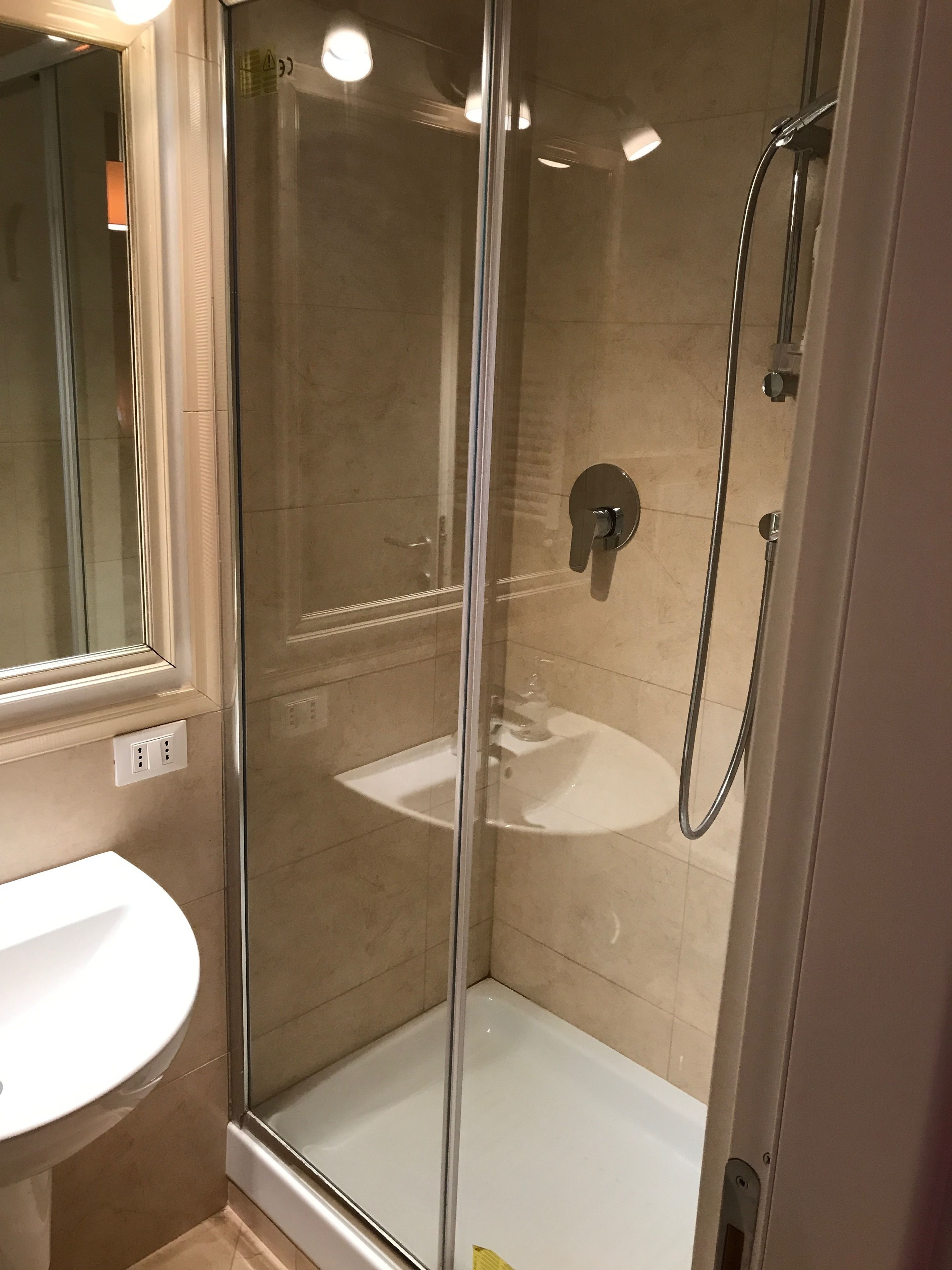 A glass-enclosed shower with a white sink and a mirror.