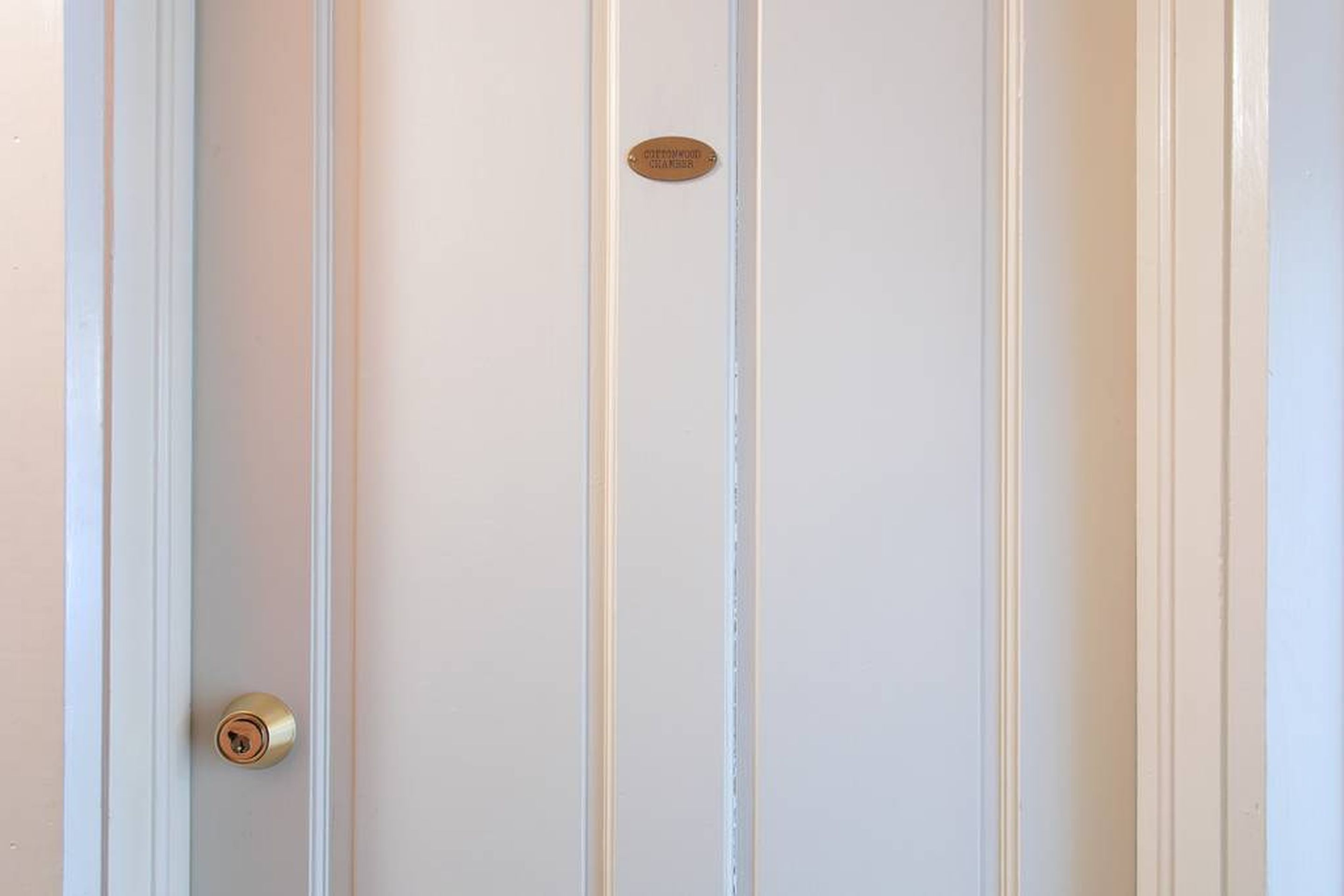 A white door with a brass doorknob and a brass plaque.