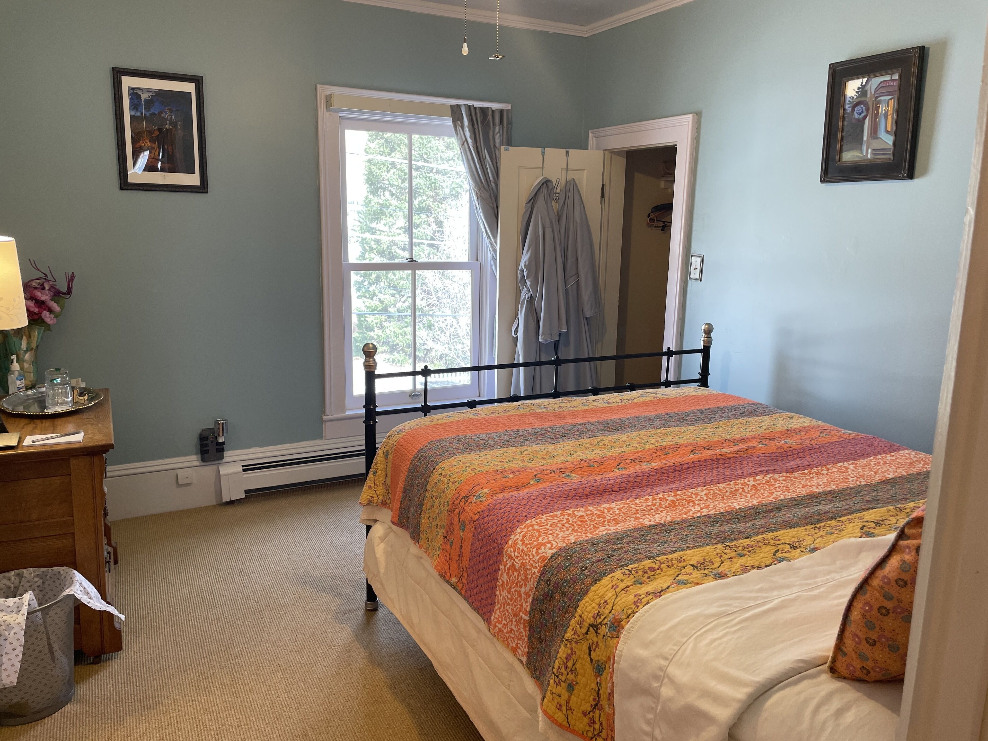 A bedroom with a bed, a window, a dresser, and a mirror.