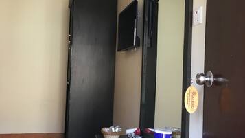 A bathroom with a dark door, a mirror, a towel, a basket, and a can of toothpaste.