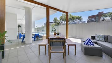 A covered outdoor patio with a dining table, benches, and a sofa.
