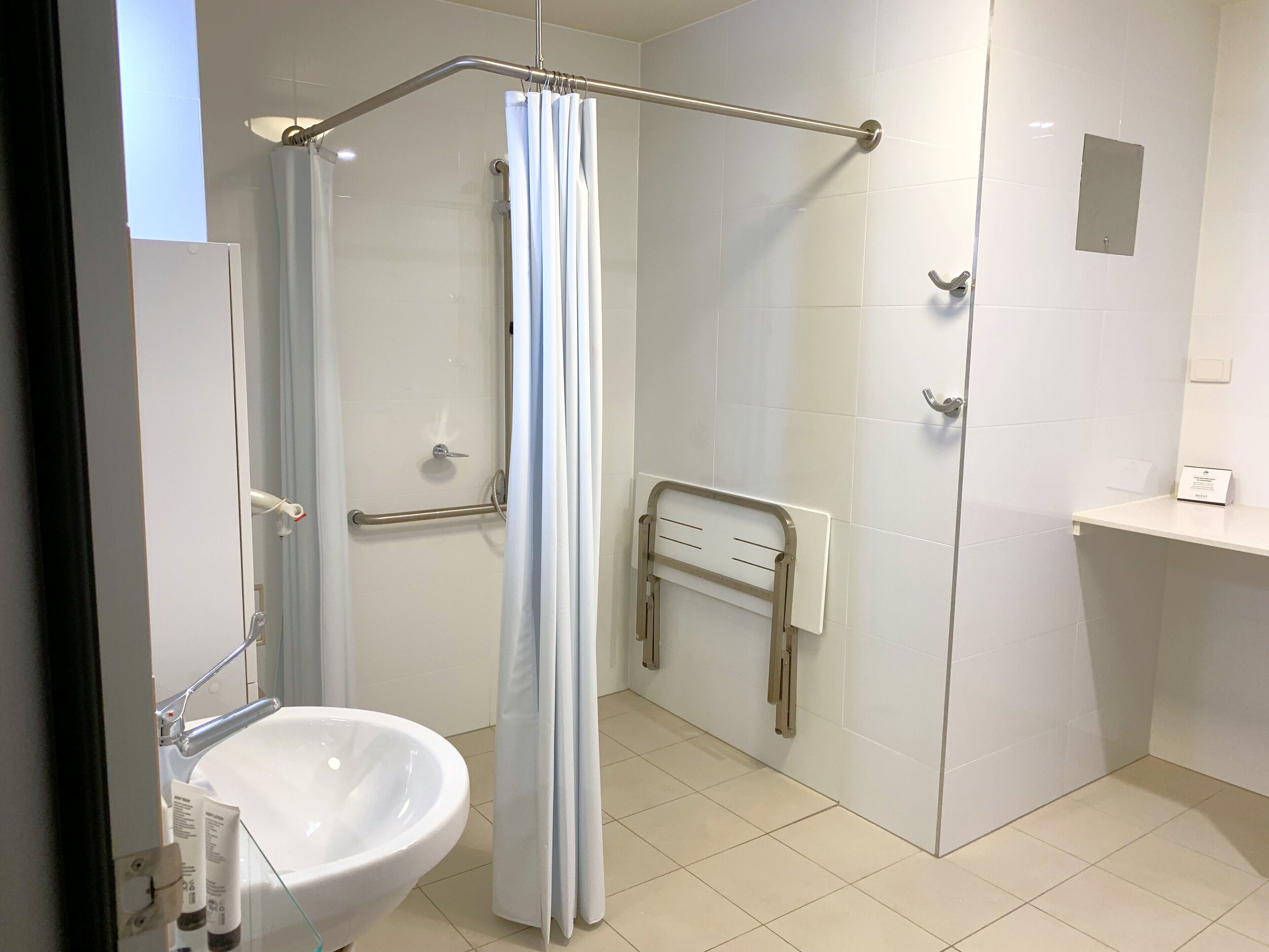 A modern bathroom with a glass shower enclosure, a white sink, and a towel rack.