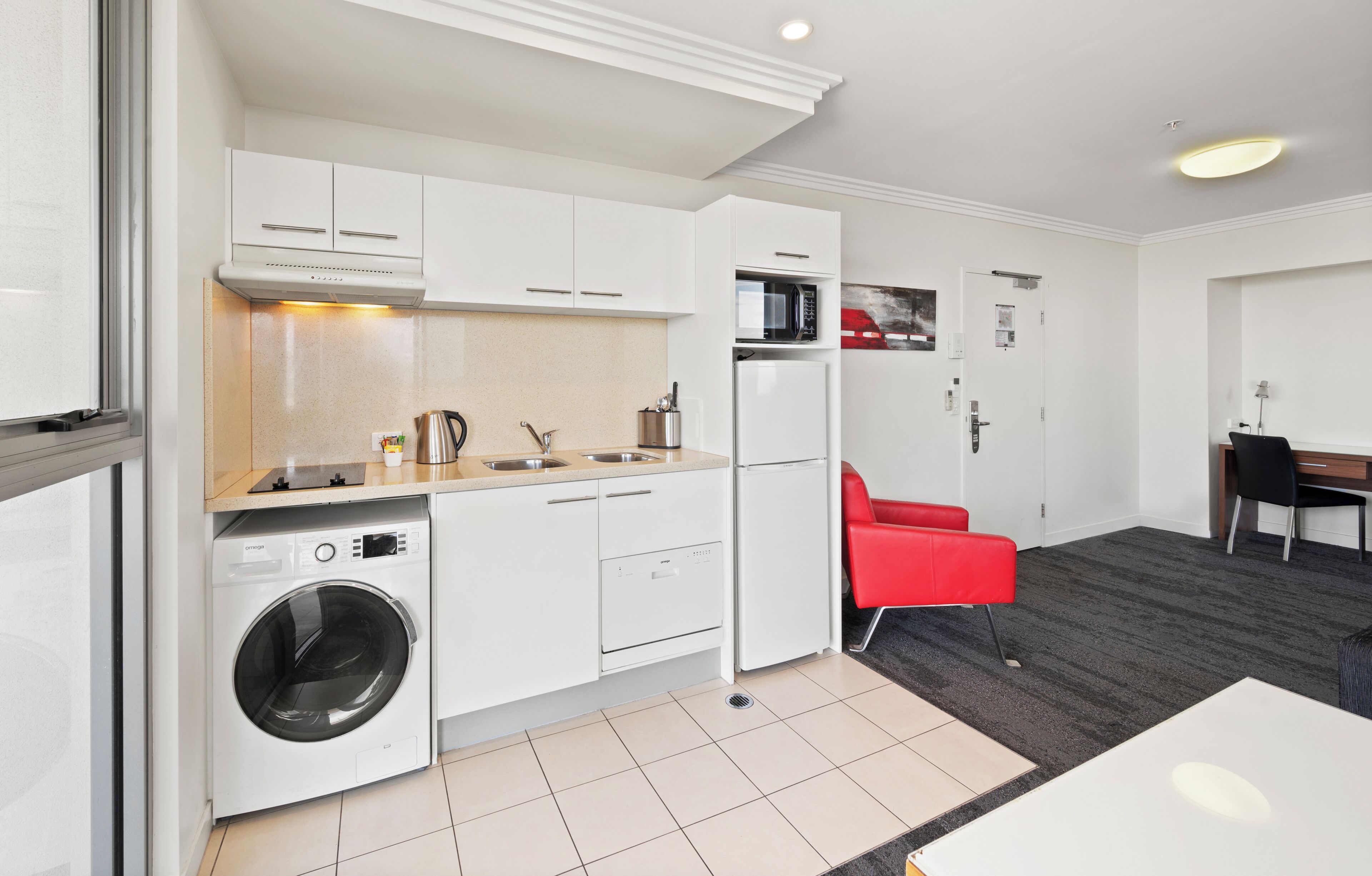 A compact kitchen with a washing machine, a microwave, and a refrigerator.