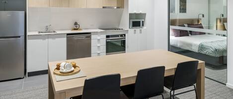 Une cuisine moderne avec une table et des chaises en bois, un four à micro-ondes et un réfrigérateur.