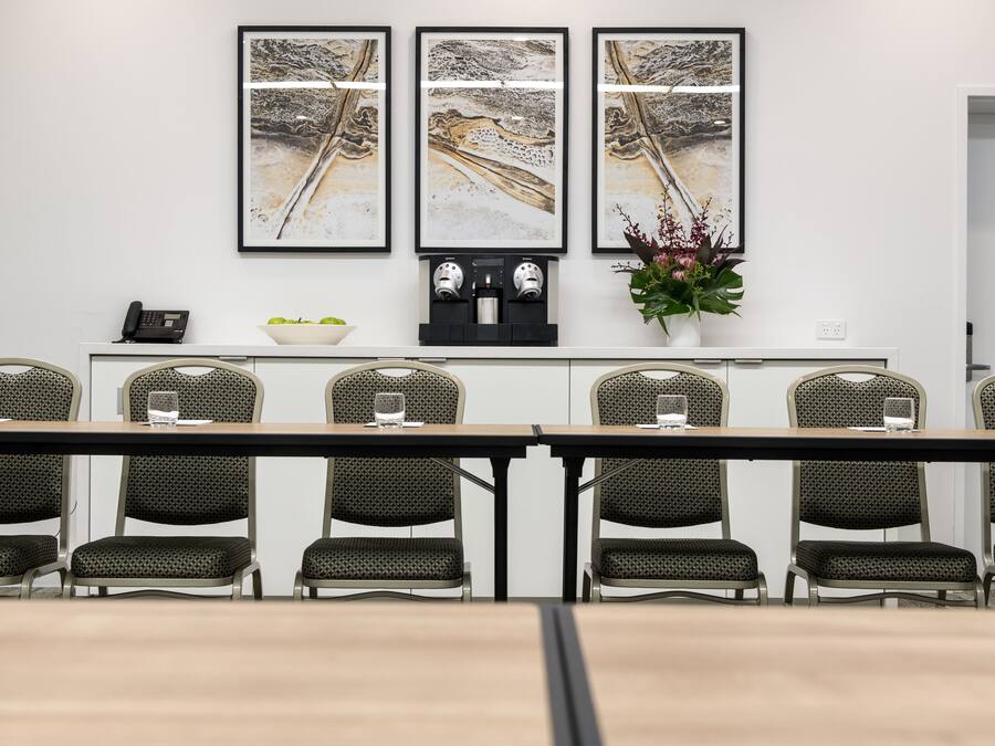 Un salón de conferencias con una mesa larga, seis sillas y tres obras de arte enmarcadas en la pared.