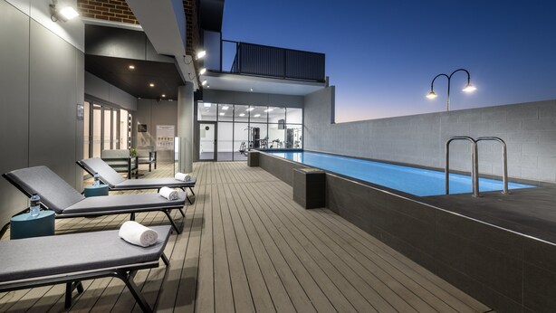 A rooftop pool area with lounge chairs and a clear view of the sky. - Quest Midland (Midland)