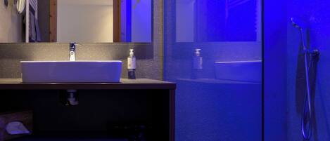 A modern bathroom with a white sink, mirror, and a shower area.