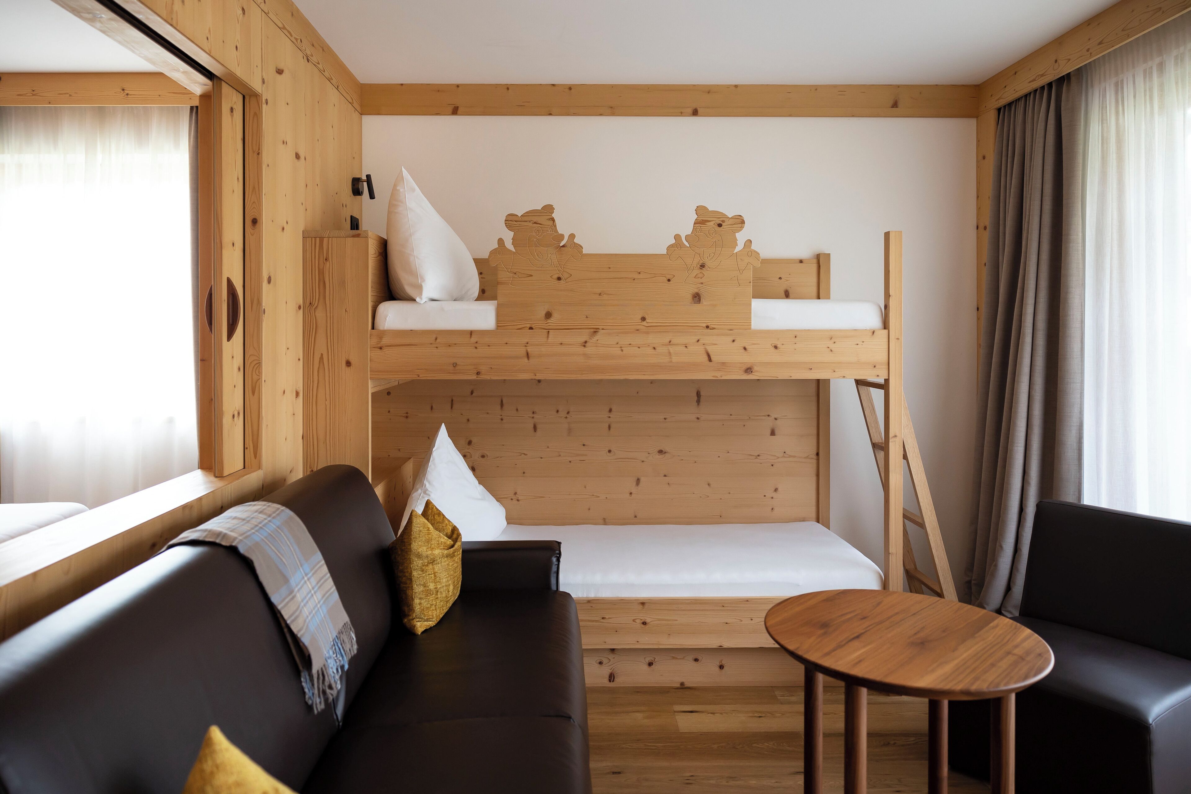 A wooden cabin interior with a bunk bed, a sofa, and a small table.