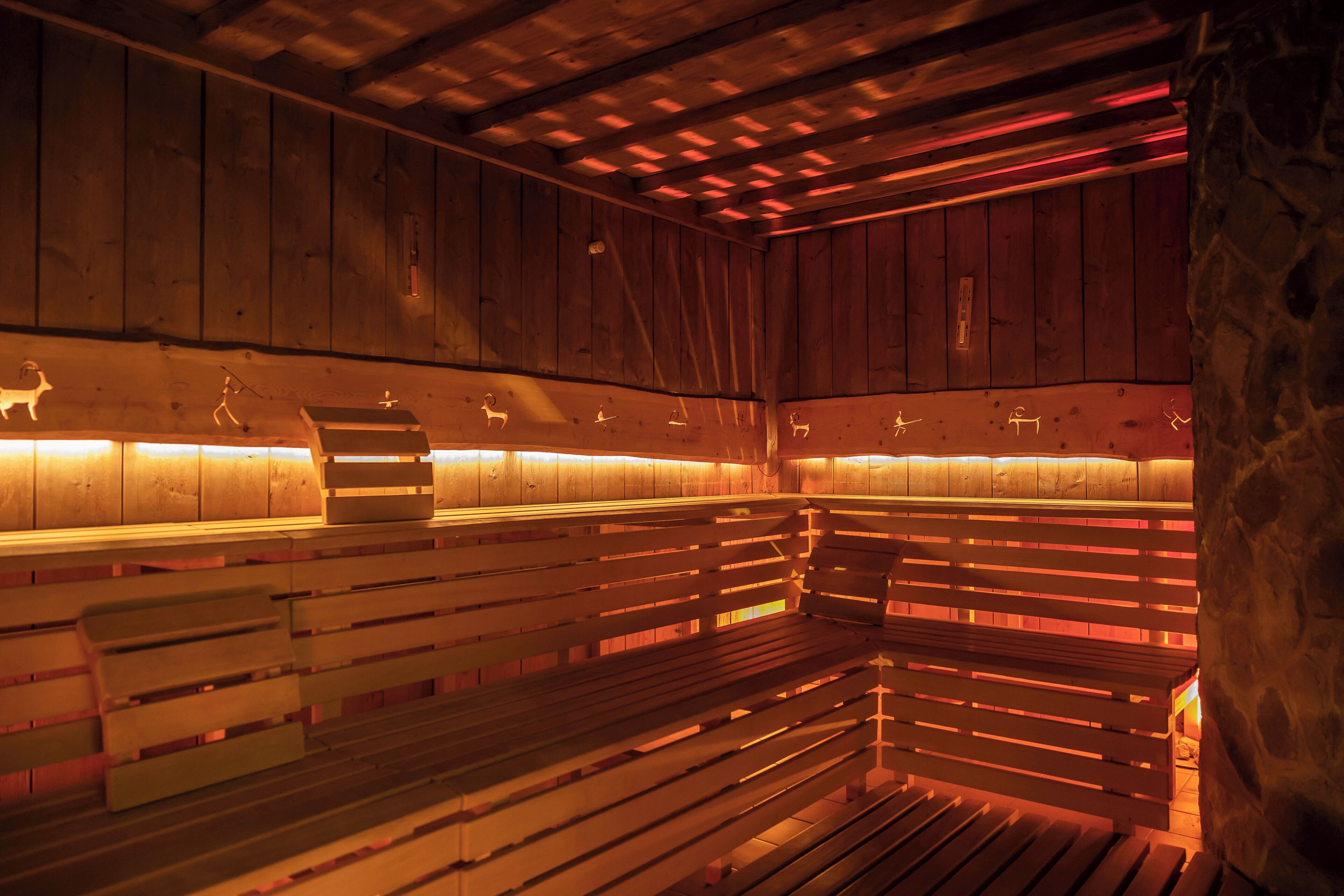 Eine Sauna mit Holzbänken und einer Steinwand.