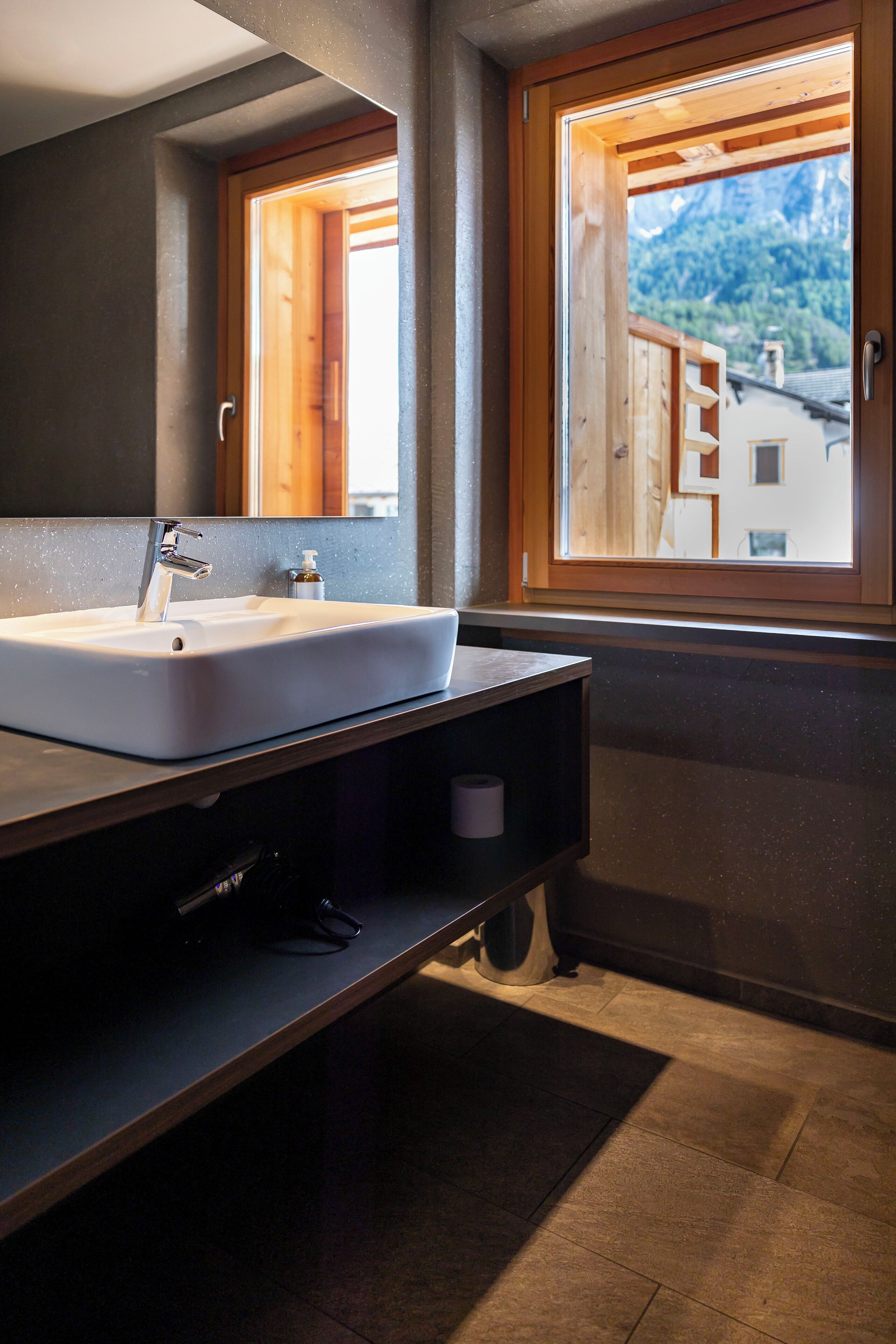 A bathroom with a large sink, a mirror, and a window with a view of mountains.